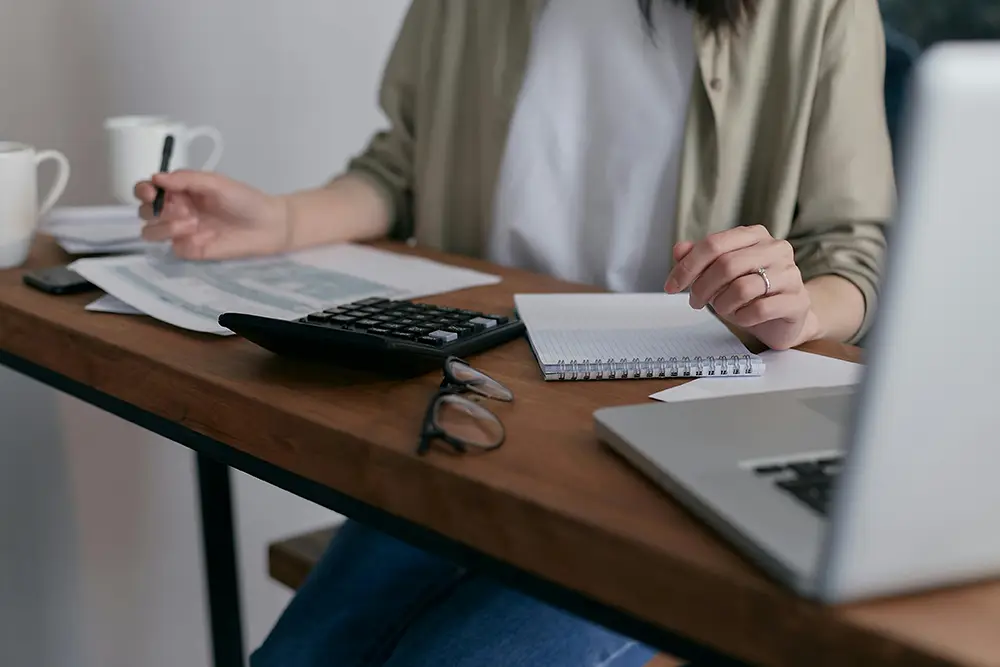 Young Lady sitting at a desk with computer and calculator